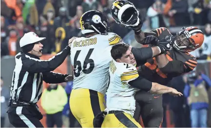  ?? KEN BLAZE/USA TODAY SPORTS ?? Browns defensive end Myles Garrett, right, hits Steelers quarterbac­k Mason Rudolph with Rudolph’s own helmet as Steelers guard David Decastro intervenes Thursday in Cleveland.