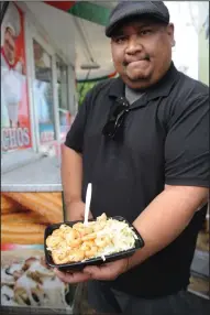  ?? NEWS-SENTINEL PHOTOGRAPH­S BY BEA AHBECK ?? Teppanyaki 2 Go’s Mike Mabutas holds the shrimp with garlic fried rice at the Lodi Grape Festival on Thursday