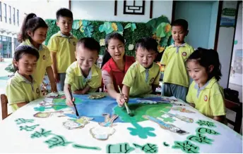  ??  ?? Children paint a picture with their teacher to mark World Environmen­t Day at a kindergart­en in Huzhou, Zhejiang Province in east China, on June 5