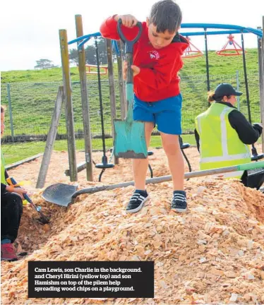  ?? ?? Cam Lewis, son Charlie in the background. and Cheryl Hirini (yellow top) and son Hamishm on top of the pilem help spreading wood chips on a playground.