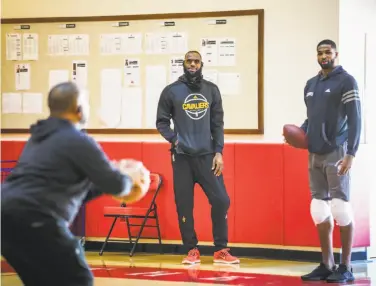  ?? Gabrielle Lurie / The Chronicle ?? LeBron James (center) watches and Tristan Thompson holds the wrong kind of ball at the Cavs’ workout.