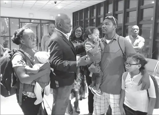  ??  ?? Minister of Citizenshi­p Winston Felix (second from left) interacts with the Grimmonds who returned home last night from The Bahamas. They are the first family to return from the island that was ravaged by Hurricane Dorian.