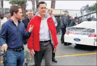  ?? By Terry Renna, AP ?? Turn right, not left: Presidenti­al candidate Mitt Romney, right, and driver Brian Vickers talk near a car sponsored by Rick Santorum.