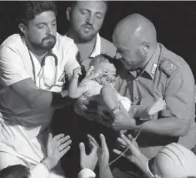  ??  ?? Rescuers pull out seven-month-old Pasquale from the rubble of a building in Casamiccio­la, on the Italian island of Ischia.