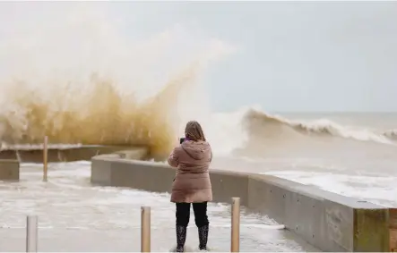  ?? — AFP ?? A woman takes photos of waves crashing against a tidal wall in Asnelles, northweste­rn France. 2018 will be a big year for the Paris climate agreement.