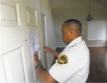  ?? Paul Chinn / The Chronicle 2008 ?? Contra Costa County Sheriff ’s Deputy Doug Odom posts an eviction notice at an Antioch home in 2008, during a recession that cost millions their homes.