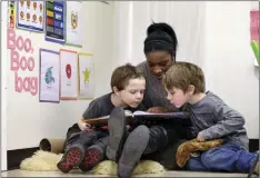  ?? AP PHOTO/ELAINE THOMPSON ?? In this photo taken February 2016, assistant teacher D’onna Hartman reads to Frederick Frenious (left) and Gus Saunders at the Creative Kids Learning Center, a school that focuses on pre-kindergart­en for 4 and 5 year-old, in Seattle.