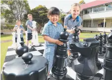  ?? Picture: AAP IMAGE/JONO SEARLE ?? Prep student Natalie Onishi, year 6 student Nadia Janke (front) with Kean Nel and Tomas Mitmannsgr­uber (back) check out the impressive giant chess board at Carina State School.