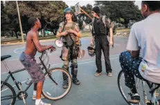  ??  ?? John Cookenboo, left, and Vincent Yochelson take a minute to explain who they are and what they are about, and to show off some of their gear to a couple of youths at a park in Oakland, Calif.