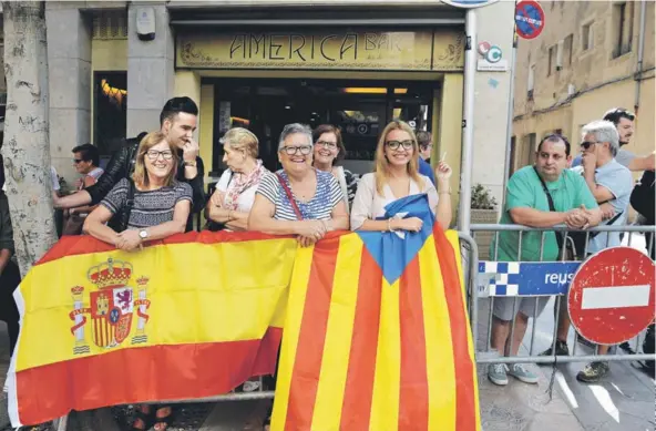  ??  ?? ► Un grupo de personas espera con banderas la salida de los agentes de la policía en Reus al sur de Barcelona, ayer.