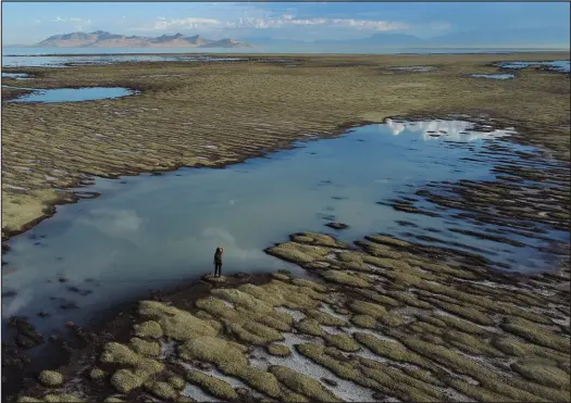  ?? RICK BOWMER / ASSOCIATED PRESS PHOTOS ?? Angelic Lemmon, a park ranger for Utah’s Department of Natural Resources, walks across reef-like structures called microbiali­tes, exposed by receding waters at the Great Salt Lake on Sept. 28, 2022, near Salt Lake City.