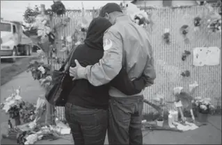  ?? JAY L. CLENDENIN, TNS ?? Mourners hug next to flowers near the site of the warehouse fire Sunday in Oakland, Calif.