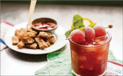  ??  ?? Southerner­s love sweet tea, and they love watermelon. We mix the two into a refreshing summer libation, garnished with lemon, mint and frozen watermelon balls. In the background is fried watermelon rind.