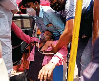  ?? SAJJAD HUSSAIN / AGENCE FRANCE-PRESSE ?? A man breathes with the help of oxygen on a roadside in Ghaziabad on April 26 as India’s health system is overwhelme­d.