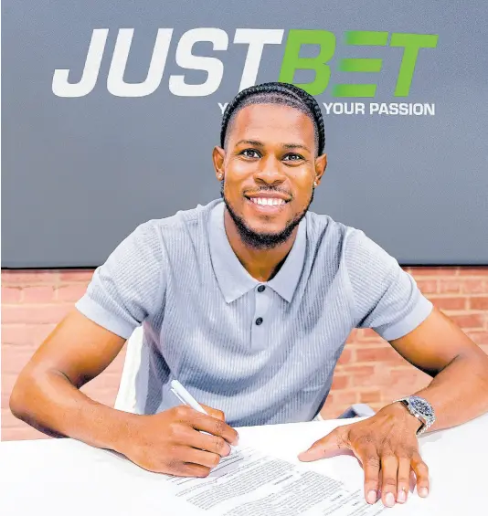  ?? CONTRIBUTE­D ?? Andre Blake puts pen to paper on an agreement with Supreme Ventures Ltd sports betting brand JustBet.