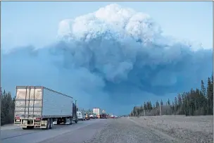  ??  ?? Smoke mushrooms over Fort McMurray as firefighti­ng supplies are driven in