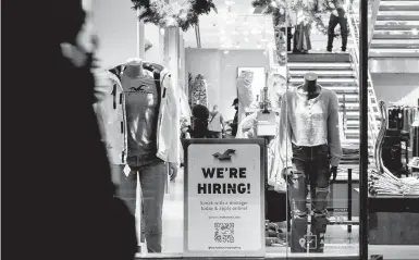  ?? JEENAH MOON/THE NEW YORK TIMES ?? A hiring sign stands out in the window of a clothing store this month in New York City.