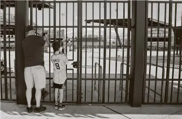  ?? Sue Ogrocki / Associated Press ?? Chicago Cubs fans take photos through the locked gates of Sloan Park — the spring training site of the team — in Mesa, Ariz., in March 2020 when MLB suspended preseason play because of the coronaviru­s outbreak.