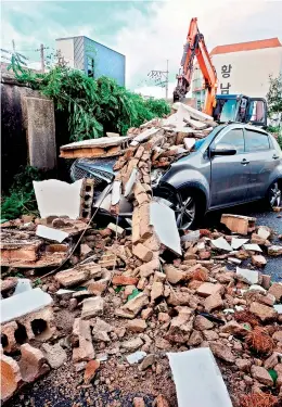  ?? —AFP ?? A damaged car is seen under a wall broken by Typhoon Maysak in the southeaste­rn port city of Ulsan on Thursday. At least one person was killed and more than 2,000 people evacuated to temporary shelters in South Korea.