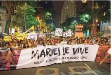  ??  ?? Manifestan­tes sostienen una manta con la frase “Marielle vive” durante una protesta contra el crimen de la concejal Marielle Franco.