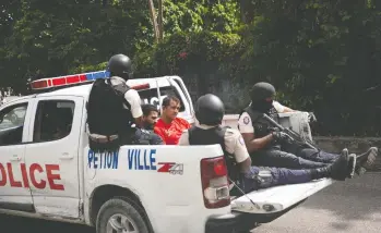  ?? JOSEPH ODELYN / AP PHOTO ?? Police escort two detainees in Port-au-prince, Haiti, on Thursday. According to Police Chief Leon Charles,
the two detained men are suspects in the assassinat­ion of Haitian President Jovenel Moïse.