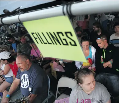  ?? JOHN MOORE/GETTY IMAGES ?? People await dental treatment Saturday as part of a massive free health-care clinic at a county fairground in Wise, Va. The event, held by the charity Remote Area Medical, was staffed by volunteer doctors and nurses, and saw thousands of people without...