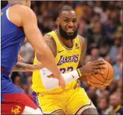  ?? JUSTIN TAFOYA — GETTY IMAGES/TNS ?? The Lakers' LeBron James drives to the basket against the Nuggets during the season opener Tuesday at Denver. James scored 21 points in his 29 minutes on the floor.