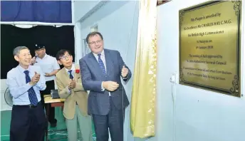  ??  ?? Hay (right) unveils a plaque in the naming of the hall, witnessed by (from left) Dr Yao and Ang.