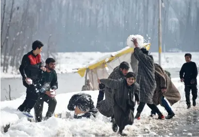  ?? AFP ?? Kashmiri youths play with snow on the shores of Dal Lake after snowfall in Srinagar on Saturday. —