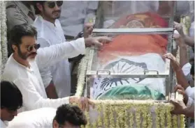  ??  ?? Indian Bollywood actor Anil Kapoor (left) stands with the body of actress Sridevi Kapoor (center) in the funeral cortege as they reach the crematoriu­m for the final rites in Mumbai yesterday.