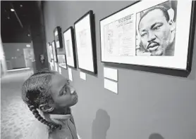  ?? AMY DAVIS/BALTIMORE SUN ?? Tinerria Gray, of Baltimore, looks at a photograph of Martin Luther King framed with a copy of the Lincoln Memorial Program for the March on Washington for Jobs and Freedom, dated August 28, 1963, while visiting the Reginald F. Lewis Museum of Maryland African American History & Culture.