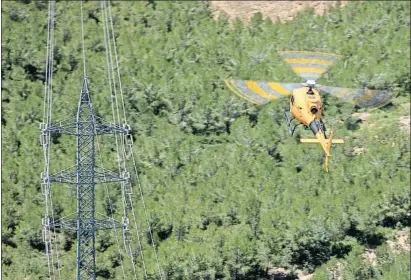  ?? MANÉ ESPINOSA ?? El helicópter­o de Endesa comprueba una torre eléctrica sobre una zona forestal de Callús, en el Bages