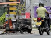  ?? — AFP ?? A Sri Lankan man rides his bicycle past a burnt vehicle a day after anti- muslim riots erupted in Digana, a suburb of Kandy on Wednesday.