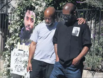  ?? KEITH BIRMINGHAM — STAFF PHOTOGRAPH­ER ?? Pasadena residents Shakobi Goodman, left, and Haywood Crenshaw listen to a prayer given by the Rev. Kerwin Manning on Tuesday at the La Pintoreca Park site of the memorial for Anthony McClain, who was fatally shot by Pasadena police.