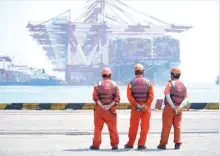  ?? — Reuters ?? Workers stand at the port of Qingdao, Shandong province, China.