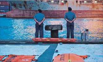 ?? ED WRAY GETTY IMAGES ?? Policemen wait for a navy ship bringing further wreckage of Lion Air flight JT 610 at the Tanjung Priok port on Monday in Jakarta, Indonesia. Lion Air Flight JT 610 crashed shortly after take-off.