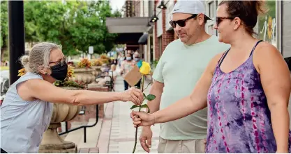  ??  ?? Barb Shepherd (left) hands out roses during a Black Lives Matter protest in June. With some in the community fearing violence from the protest, the best thing to do was spread love, Shepherd said. (Photo by Canovas Photograph­y)