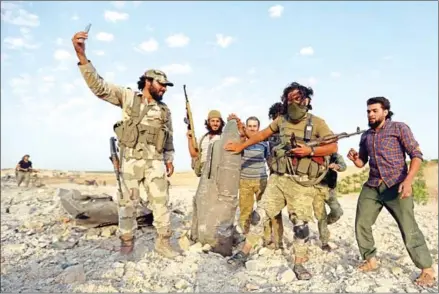  ?? OMAR HAJ KADOUR/AFP ?? Rebel fighters pose for a picture with the remains of a downed regime warplane near the jihadist-held town of Khan Sheikhun in the south of Idlib province on Wednesday.