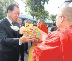  ?? ceremony. SOMCHAI POOMLARD ?? RIGHT Worachai Bhicharnch­itr, director and member of the Bangkok Post executive committee, joins staff in giving alms to a monk during the meritmakin­g