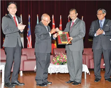  ??  ?? Hashim (second from left) presenting a memento to Mazlan.