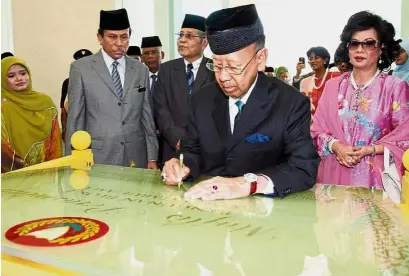 ??  ?? Official duty: Tuanku Abdul Halim signing a plaque to officially open the new Block E complex of Wisma Darul Aman in Alor Setar on Feb 19, 2009. Looking on is Sultanah of Kedah Tuanku Haminah Hamidun (right).