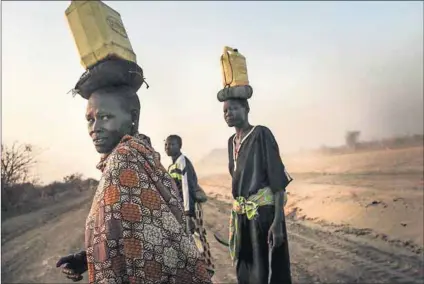  ?? Photo: Spencer Platt/Getty Images ?? Meagre supplies: Women walk to their village on the outskirts of Juba in South Sudan with small containers of water. Safe drinking water is scarce throughout the war-ravaged country.