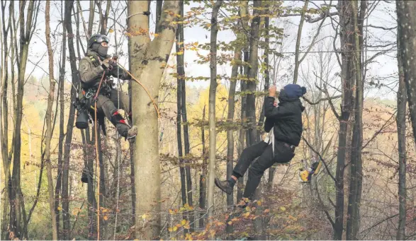  ??  ?? Polizisten holen bei einem Großeinsat­z im Dannenröde­r Forst Klimaaktiv­ist*innen aus den Bäumen.