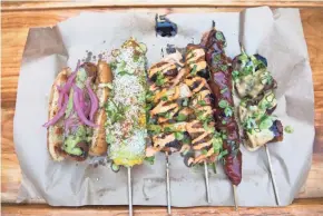  ?? TYGER WILLIAMS, MILWAUKEE JOURNAL SENTINEL ?? At Lost Whale, Iron Grate's lineup includes sausage on a bun, corn on the cob, mushroom and green onion, pork belly, pork loin and skewered sausage.