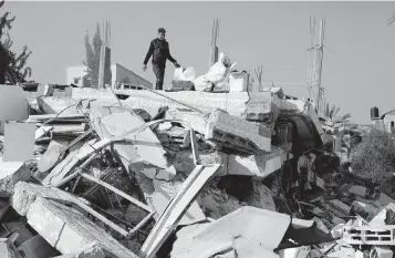  ?? KHALED OMAR USA TODAY NETWORK ?? A man is seen on the rubble of a destroyed building after an Israeli airstrike in the southern Gaza Strip city of Rafah, on Monday. The Palestinia­n death toll claims the death toll from ongoing Israeli attacks in the Gaza Strip has risen to 29,782, the Hamas-run Health Ministry said in a press statement Monday.