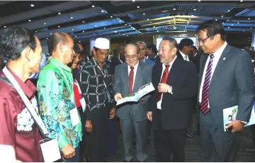  ??  ?? Uggah (centre), accompanie­d by Dr Abdul Rahman (right), Sagah (second right) and some delegates, looks at the programme booklet and promotiona­l items at ICAAS 2018.