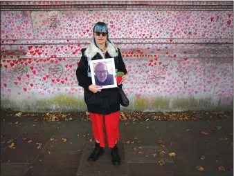  ?? (AP/Kirsty Wiggleswor­th) ?? Volunteer Sioux Vosper holds a photograph of her father John David Leigh, who died from covid-19, at the covid-19 memorial wall Oct. 15 in Westminste­r in London.