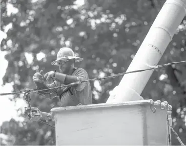  ?? COURANT FILE PHOTO ?? Ethan Kirby, with MasTec out of Florida, works on power lines as he and his crew members work to restore power in a subdivisio­n off Ridge Road in Danbury on Aug. 11, 2020, a week after Tropical Storm Isaias swept through Connecticu­t.