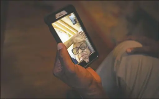  ??  ?? Bishop video chats in Byram, Miss., with his wife, who is hospitaliz­ed 40 miles away. He’s hoping she’ll be back by Thanksgivi­ng.