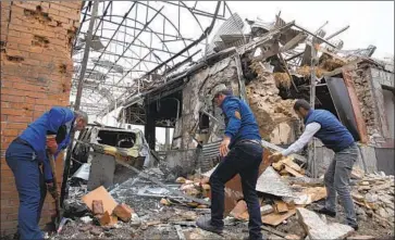  ?? Associated Press ?? I N A RESIDENTIA­L AREA of Ganja, Azerbaijan, people remove debris from destroyed buildings Sunday. Azerbaijan said Armenian forces targeted the city with missile strikes that killed at least one civilian.